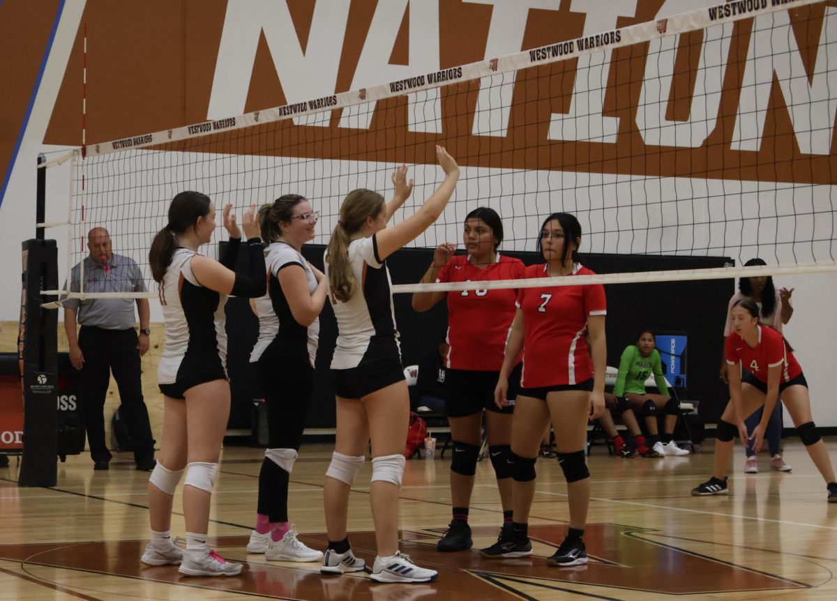 The Warriors stand at the net during a serve in an attempt to intimidate the Mustangs. The Warriors played hard making sure they didn't get behind or lose their lead. 