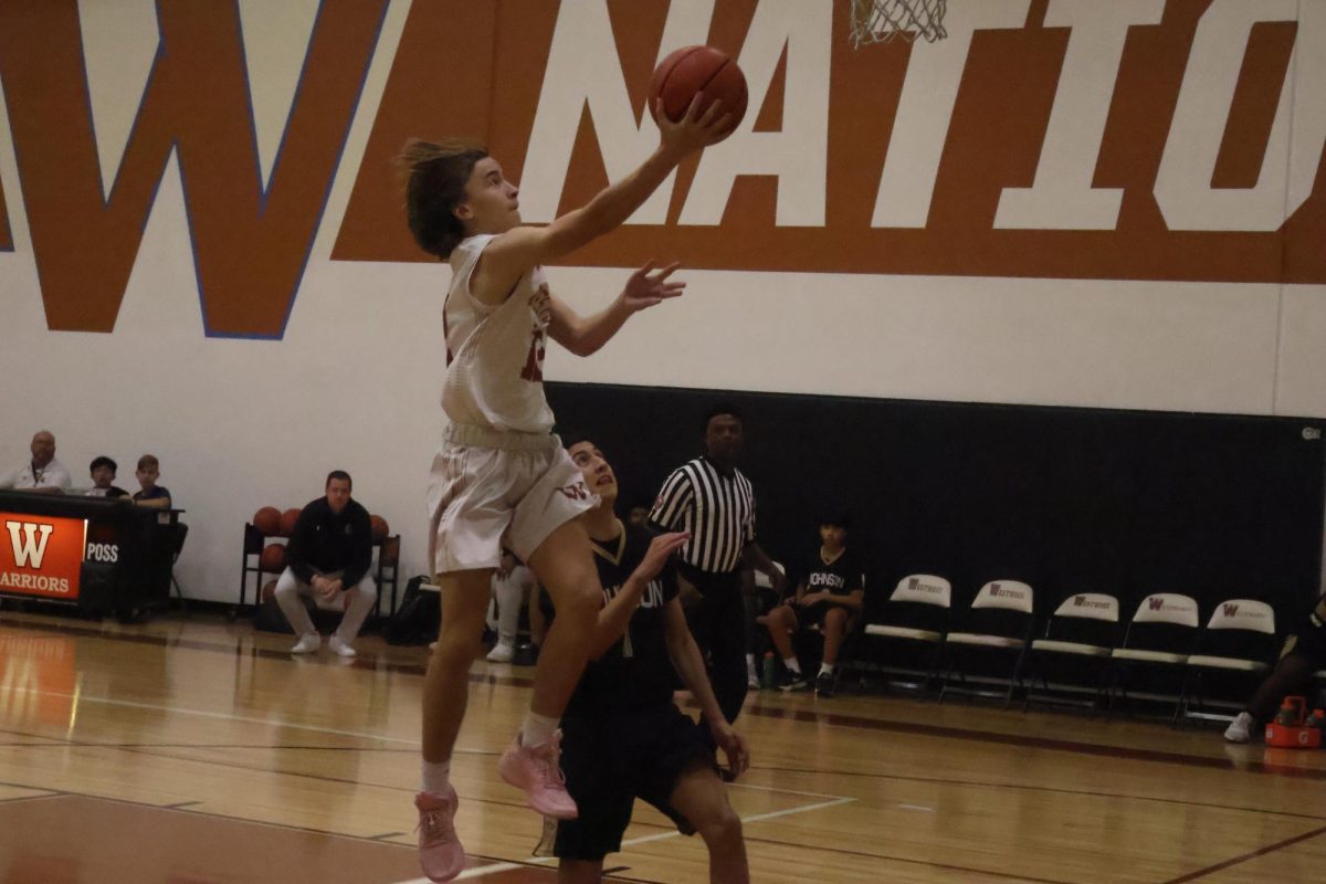 Making a layup Charlie King '27 soars up to the rim to lay it in. He dodged a block after running across the court to make the basket, and gave the Warriors a brief lead.