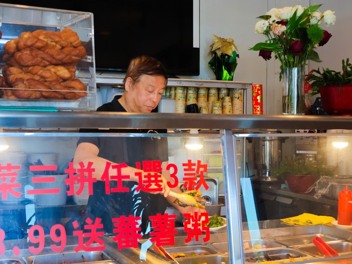 Clasping the tongs, Mr. Carey Shao places garnished eggplant on a small dish. Breakfast House puts on display a daily changing variety of classic Chinese cold dishes. 