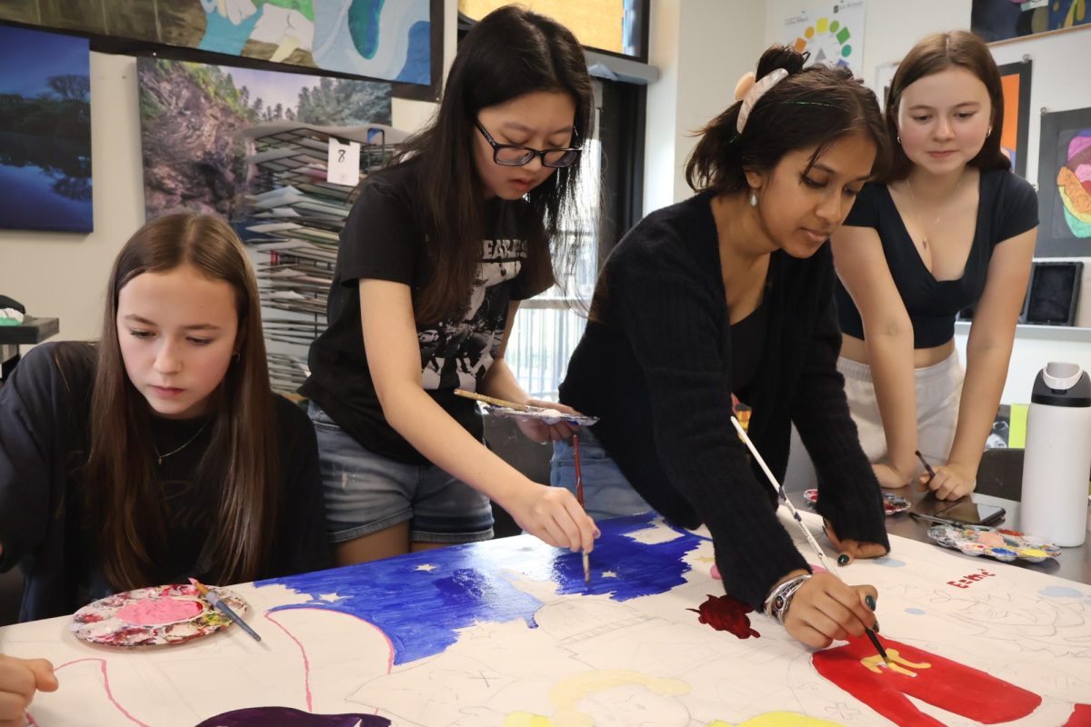 Deeply concentrated, Ava Stidvent '28, Evelyn Stidvent '26, Shrika Prakash and Hannah Son '25 paint the superheroes and the night sky of the teacher appreciation mural. Surrounding artists join in, working on painting the history and science characters. "It's really great to give back to the local middle school [CVMS] and I also think the concept is really cool to represent teachers as superheroes," Prakash said.