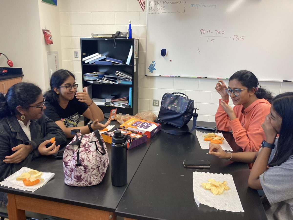 Socializing, Ananya Chiluveru '24 and Mehek Patro '24 enjoy snacks and talk across the table to other club members. Attendees played board games for the annual social event.