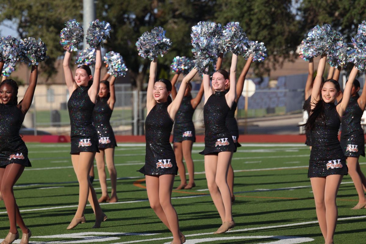 Grinning, Sophia Huang '24 raises her hands with grace in the pom dance. 