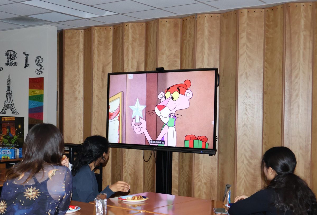Settling in with their snacks, French Club members watch "Pink Panther: A Pink Christmas". Officers planned this event for a month, and were dedicated to execute it before midterms week. “[The cartoons were] really comedic,” French Club Member Bella Yi '26 said. “I like the sort of ‘cartoony’ videos with jokes in [them], and I think it's entertaining because you don't really typically watch that at this age.”