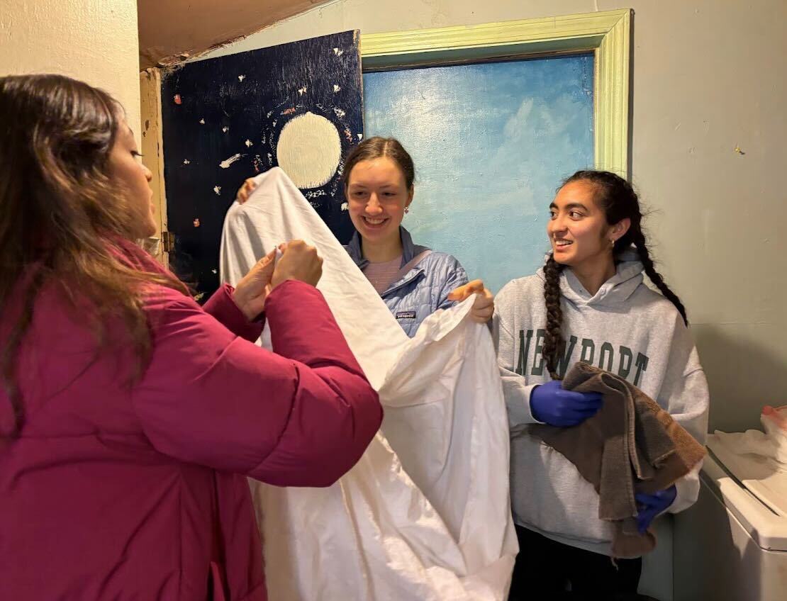 Smiling, Lena Boas '25 and Valentina Galeana Ruiz '24 fold a fitted sheet while Isabella D'Alessandro '25 folds a towel. At Casa Marianella, volunteers were tasked with organizing a linen closet. "Being able to work with others in my specified group helped me more productive," Galeana Ruiz said. 