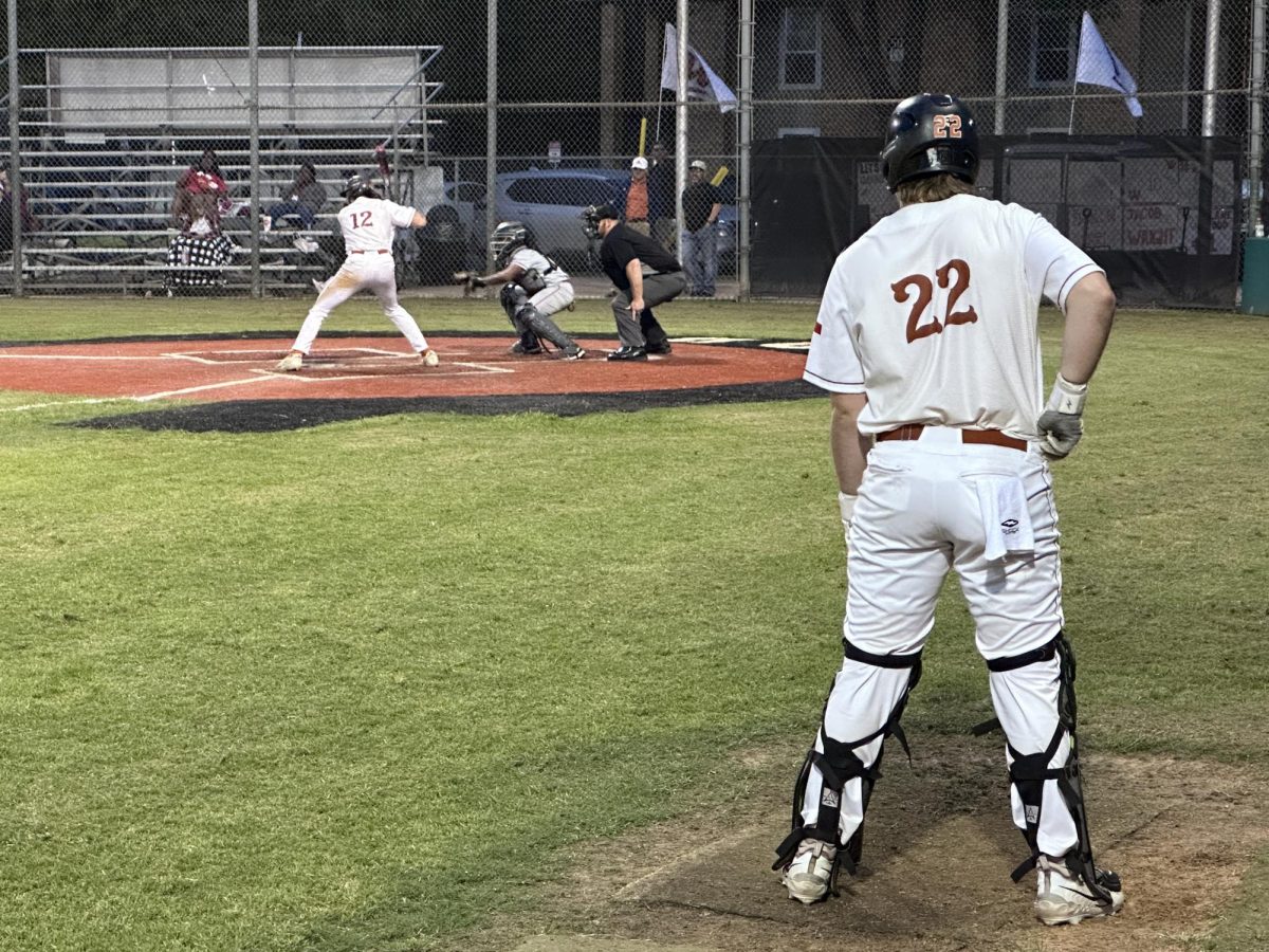Watching John Ramsey '24 prepare for a pitch, Mike Davis '24 waits on deck for his turn to bat. Because there were two out, Davis left his catchers gear on as an out would have yielded a change of possession, and Davis would head back to the plate. 