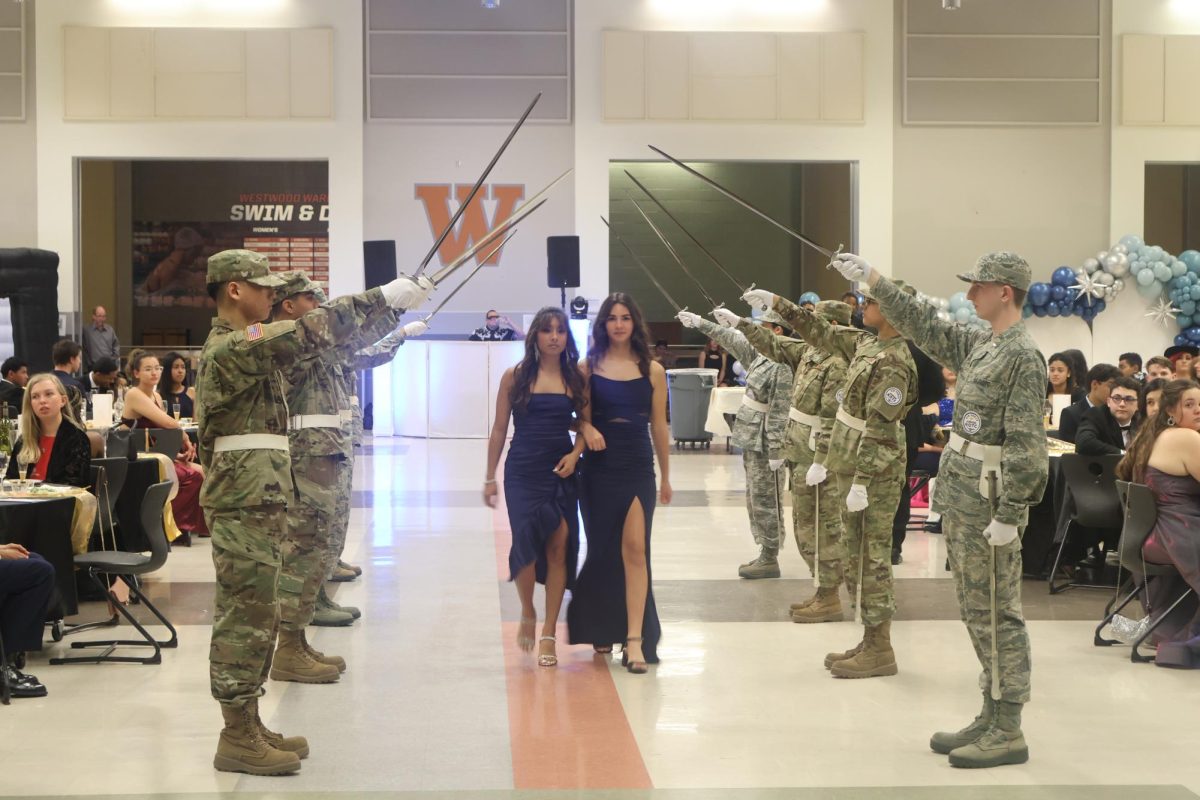 Escorted by her friend C/AB Myah Kapavik '27, C/TSgt Aliyah Mohammed '24 walks through the saber arc. Senior cadets were recognized during the ball by walking through the saber arc.