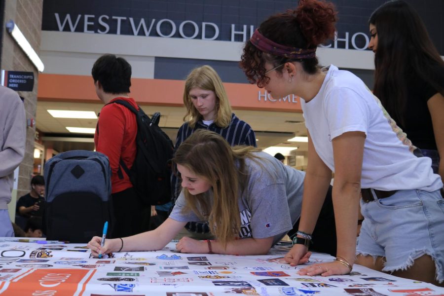 Smiling with anticipation. Sarah Taparauskuas '23 signs the college banner on May 1. She plans to attend University of Georgia in the fall.